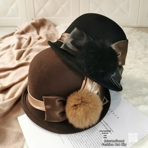 Close-up of wool cloche hats with satin ribbon bows and fluffy pom poms details