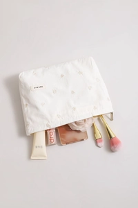 Macro view of white corduroy makeup bag with pink heart embroidery and gold zipper detail