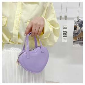 Detail of a purple heart-shaped jelly handbag in glossy finish with twin handles