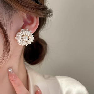 Close-up of elegant gold-plated flower cluster pearl stud earrings on a model's ear