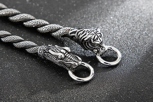 Close-up of polished stainless steel dragon and tiger heads on punk woven chain bracelet