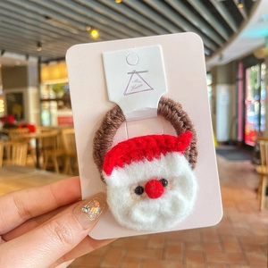 Détail d'un élastique à cheveux en tricot marron avec breloque Père Noël au crochet