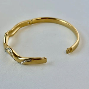Macro view of 18K gold plated wavy stainless steel bangle with pavé crystals