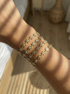Detailed view of four 18k gold plated floral bracelets with blue enamel petals and light shadows
