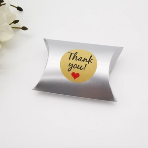 Detail der silbernen Kissen-Geschenkbox mit Metallic-Finish und gelbem Dankeschön-Aufkleber