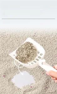 Macro view of bentonite cat litter with purple odor control beads and a plastic scoop