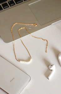 Close-up of a minimalist pearl necklace with seven white pearls on a gold chain