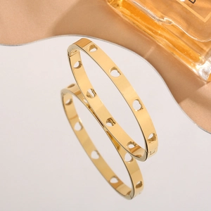 Minimalist gold heart cutout stainless steel bangle with polished mirror reflection