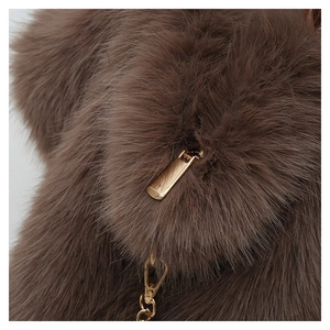 Detailed macro view of dark brown faux fur texture and a shiny gold metal zipper puller