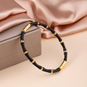 Detail eines goldenen Armreifs im Bambus-Stil mit schwarzem Emaille auf einer Schmuckbox
