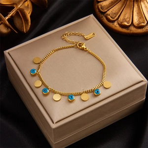 Detail of gold evil eye bracelet with blue charms on beige jewelry box with black silk