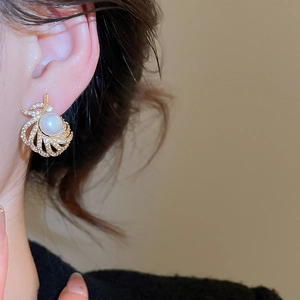 Close-up of 18k gold plated pearl drop earrings with sparkling zircon on model ear