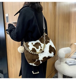 Detail of plush cow print tote bag featuring a chunky metal chain and soft furry texture