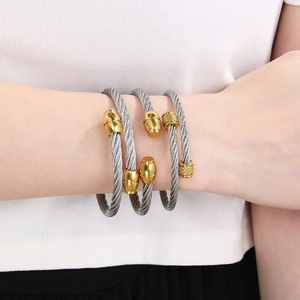 Three-piece stainless steel twisted cable bangles with gold accents on model wrist