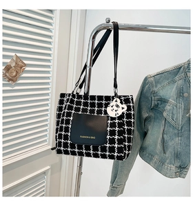 Detail of checkered tote bag with leather pocket and cute white tiger charm accessory