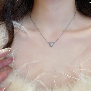 Gros plan d'un collier avec pendentif triangle argenté et zircons brillants sur un mannequin