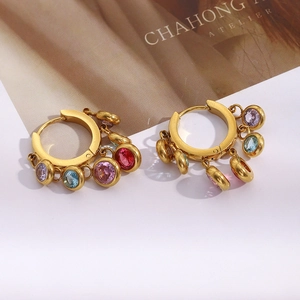 Macro detail of gold-plated hoop earrings with multi-color dangling round gemstones