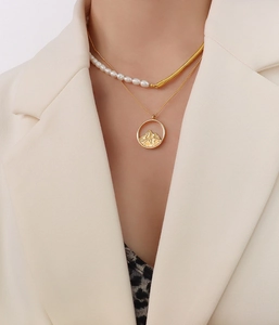 Detail of 18K gold plated chain with mountain relief pendant and pearl layered necklace