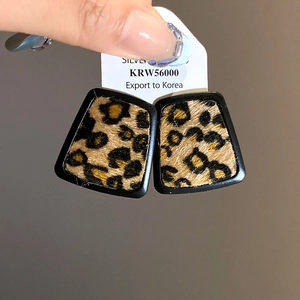 Detailed close-up of leopard print trapezoid earrings with silver needle texture and tag