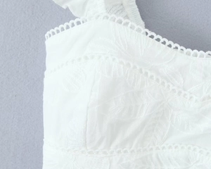 Gros plan détaillé de la broderie en dentelle blanche et du décolleté à volants du haut