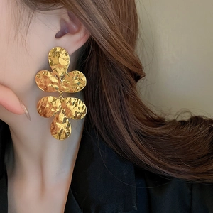 Detail of gold layered petal earrings showing hammered texture and wave metal craft on model