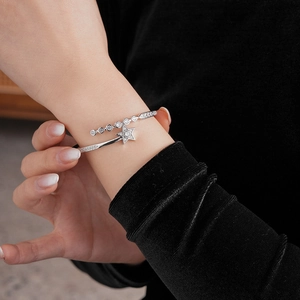 Detail of silver star cuff bracelet with sparkling zircon stones on female wrist