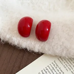Minimalist Ancora red acrylic teardrop earrings with steel pins on soft white fur
