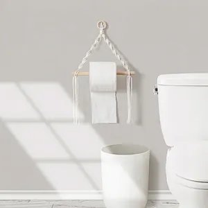 Handwoven bohemian wall tissue holder with natural cotton rope and wooden rod in a bathroom
