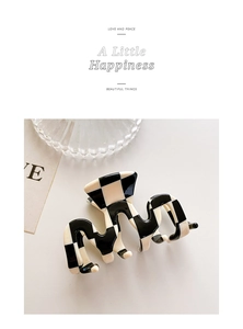 Detail of minimalist black and white checkered hair claw clip with unique wavy design
