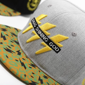 Macro detail of yellow 3D embroidery with SWAG SHINING GOD text on a hip-hop cap
