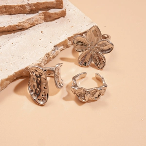 Detail of silver textured rings with floral and wavy patterns on natural stones