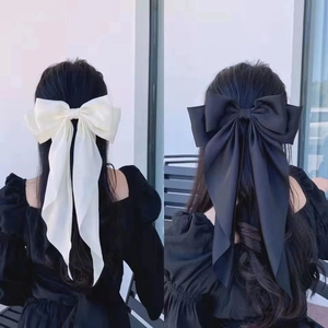 Large satin bow hair clips in black and white shown from back view on long hair