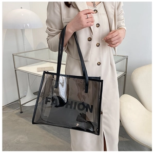 Close-up of a large black transparent PVC tote bag with Fashion text and shoulder straps