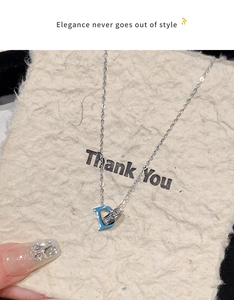 Gros plan d'un collier pendentif lettre D argenté orné de strass scintillants