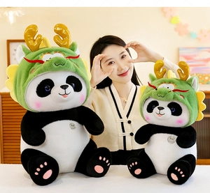 Twee panda knuffels met groene drakenmutsen, getoond met model in een gezellige kamer.