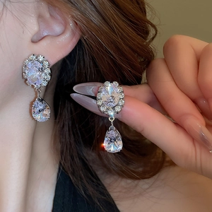 Macro view of teardrop zircon earrings with silver setting and sparkling oval stones