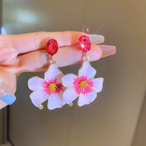 Macro detail of vintage floral drop earrings with red gems and purple petals