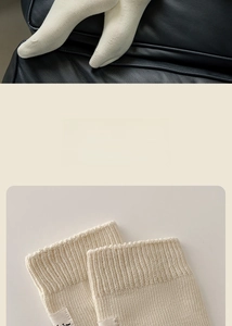 Detail of ribbed knit cuffs on cream cotton socks with minimalist woven label decoration