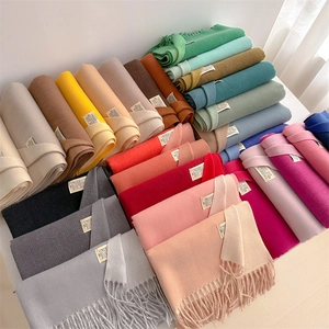 Detail view of multi-color fringe scarves in soft faux cashmere with brand labels