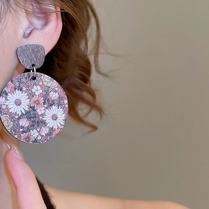Gros plan sur des boucles d'oreilles pendantes rondes en bois aux motifs floraux rétro