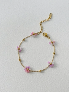 Detail of gold chain bracelet featuring pink and purple floral beads and K18 hallmark