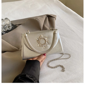 Detailed close-up of silver evening clutch featuring a sparkling rhinestone sunburst buckle