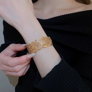 Detailed close-up of a gold hollow butterfly cuff bracelet on a model's wrist
