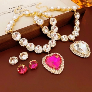 Luxurious jewelry set featuring heart pendants and round diamond earrings in warm tones