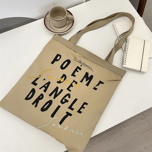 Detail of canvas tote bag featuring French poetry embroidery and minimalist art design