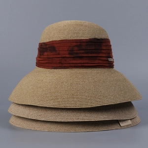 Close-up of stacked wide-brim straw hats with elegant ribbon and metal logo details