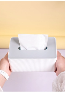 Dual-color rectangular tissue box with white body and grey lid being held by hands