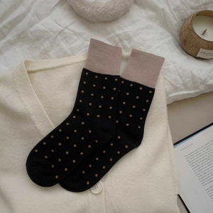 Detail of black mid-calf socks with brown polka dots and contrast nude pink ribbed cuffs