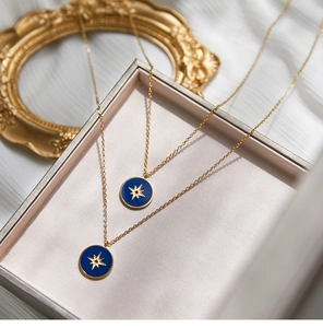 Detailed close-up of double layer gold necklaces with blue enamel star compass pendants