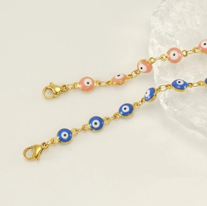 Detailed macro view of pink and blue evil eye bracelets with gold chains and lobster clasps